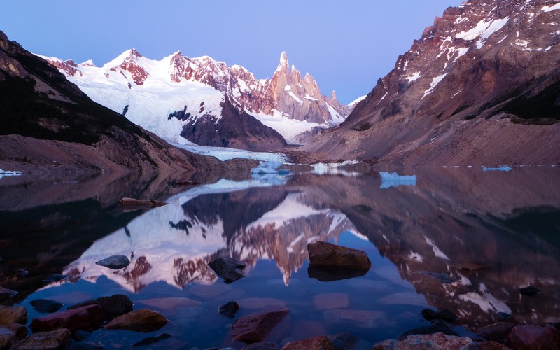 Горы, отражающиеся в озере с камнями и валунами (серро торе, cerro torre, лагуна торре, зеркальное озеро, национальный парк лос глясиарес)