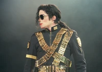 Michael Jackson con una llamativa chaqueta militar con acentos dorados y gafas de sol, personificando un estilo de actuación icónico.