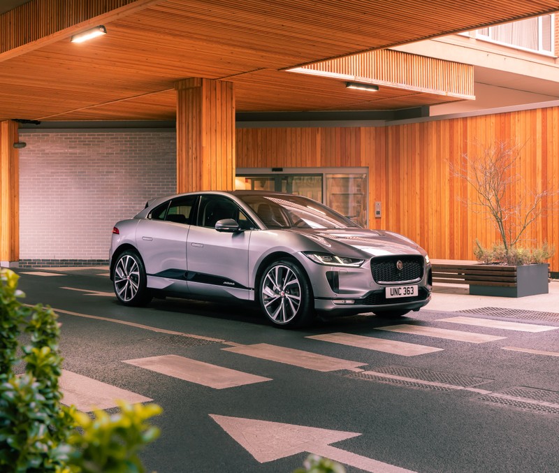 Серебряная машина припаркована перед зданием с деревянной стеной (jaguar i pace ev400 awd s black pack, 2021, 5k, машины, обои 4k)