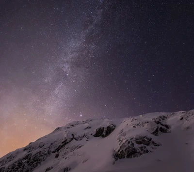 Paisaje montañoso nevado bajo un cielo estrellado.