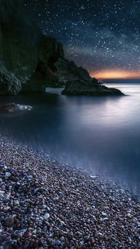 Noite estrelada sobre uma serena praia de seixos pretos