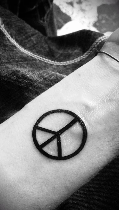 Minimalistische Friedenstattoo am Unterarm