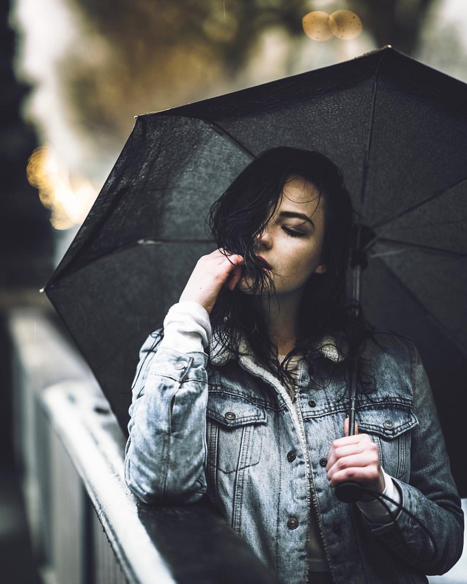 Une femme arabe avec un parapluie noir se tenant sur un pont sous la pluie (seul, fille, amour, modèle, humeur)