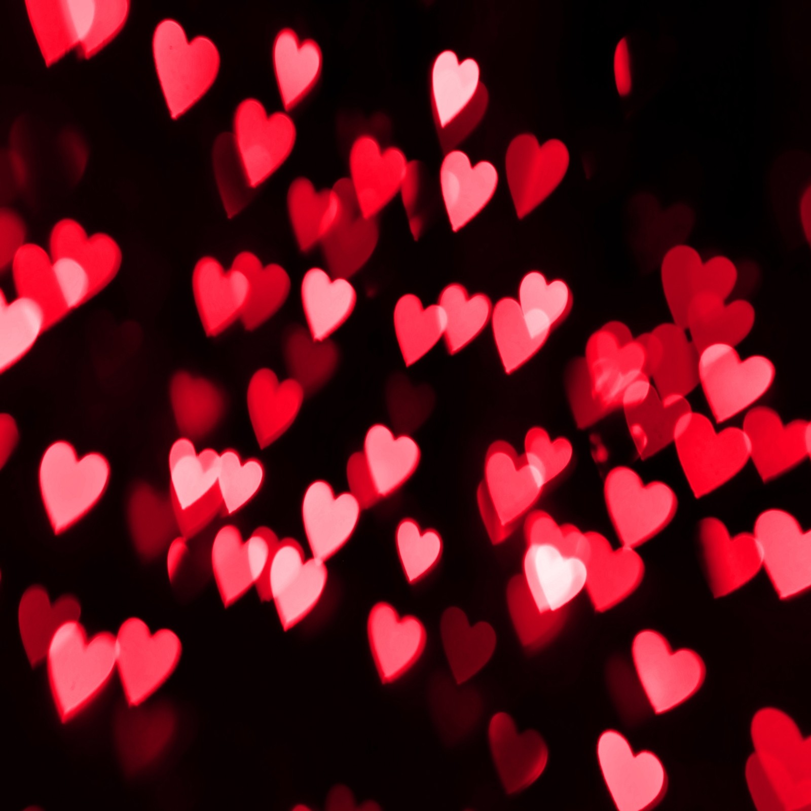 A close up of a bunch of red hearts on a black background (bokeh, heart, holiday, love, valentine)