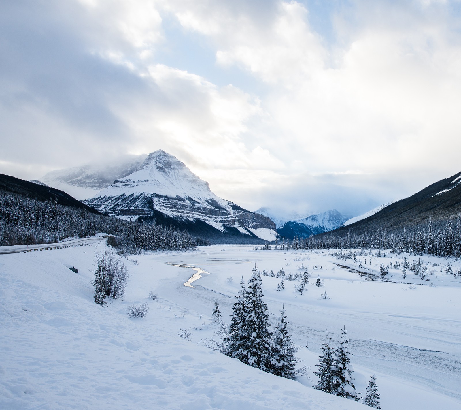 Uma paisagem nevada com um rio e montanhas ao longe (outono, neve)