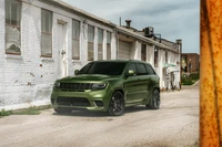 Jeep Grand Cherokee Trackhawk em um acabamento verde marcante estacionado em um ambiente industrial.