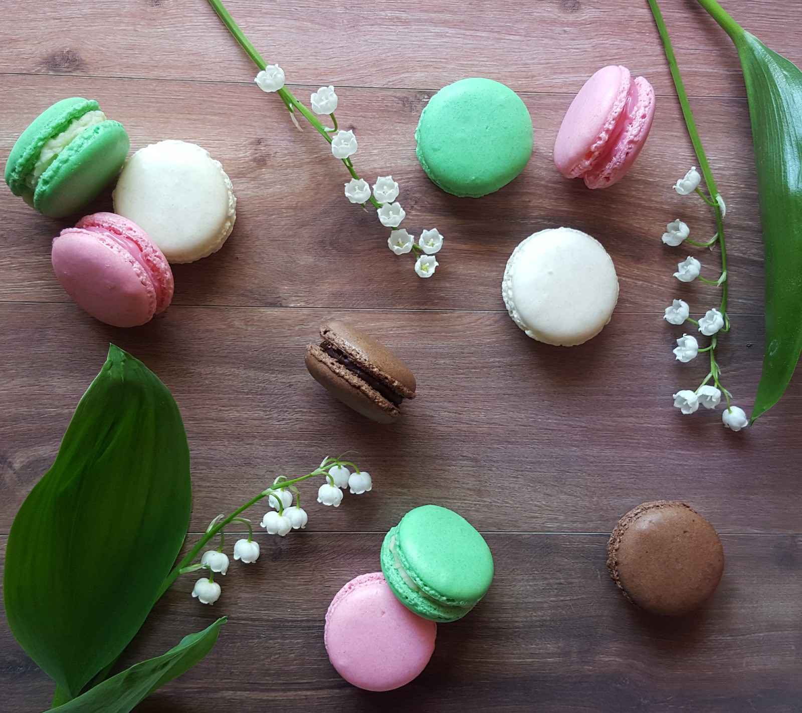 Il y a beaucoup de macarons de différentes couleurs et de fleurs sur une table (fleurs, français, lys, macarons, printemps)