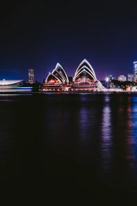 Casa de la Ópera de Sídney iluminada reflejada en aguas nocturnas