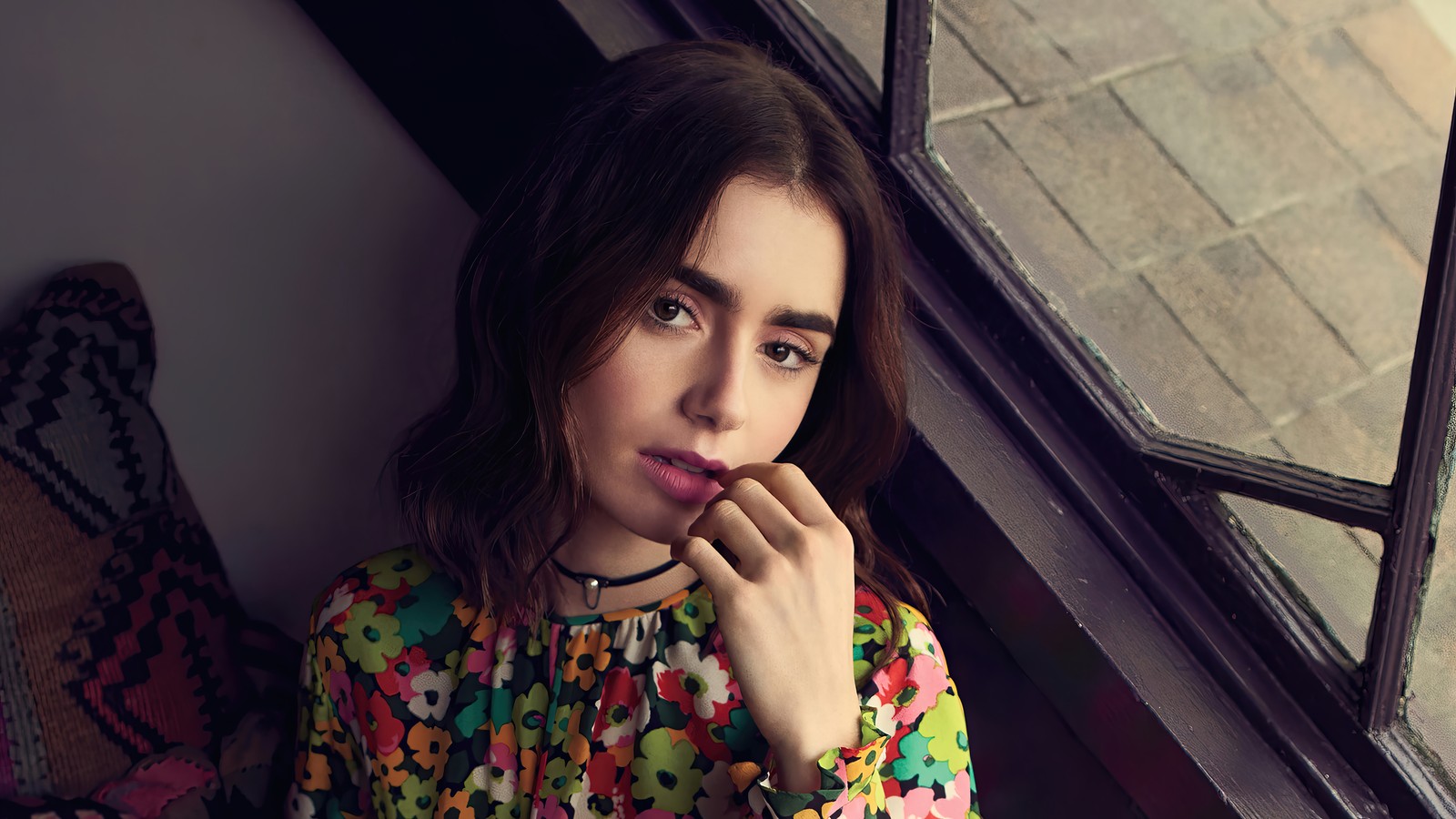 Une femme araffe est assise sur un rebord de fenêtre avec une chemise à fleurs. (lily collins, britannique, américain, actrice, célébrité)