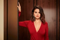 Selena Gomez in a striking red dress, showcasing elegance and beauty in a portrait photoshoot.