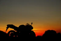 Silueta de una motocicleta contra un vibrante atardecer