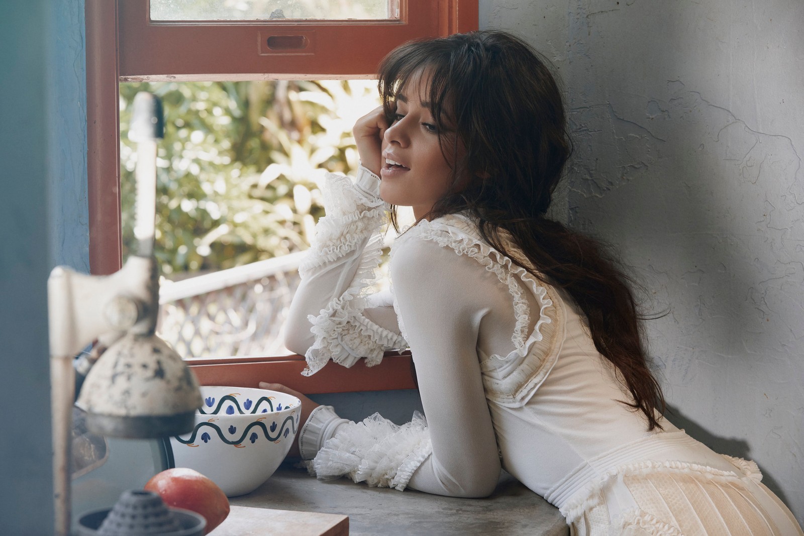 There is a woman sitting on a window sill looking out the window (sitting, long hair, window, textile, music)