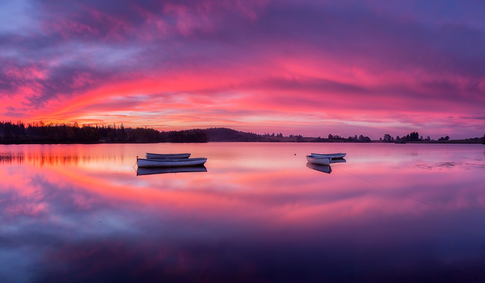 Duas barcos estão na água ao pôr do sol com um céu rosa (loch lomond, the trossachs national park, lago espelho, nascer do sol, barcos)