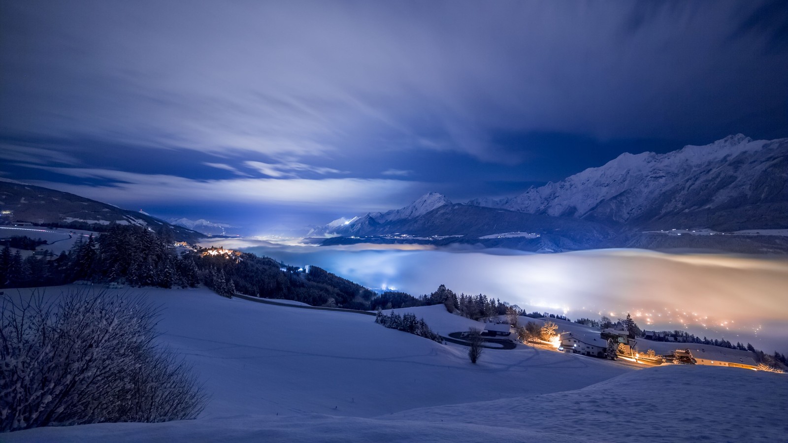 Vista nocturna de un pueblo de montaña con un valle brumoso a continuación (nieve, invierno, naturaleza, nube, congelación)