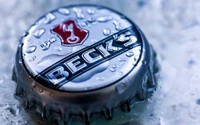 Close-up of a Beck's beer bottle cap surrounded by droplets of water and ice.