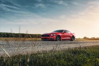 Ford Mustang rouge vibrant sur une route de gravier pittoresque au coucher du soleil