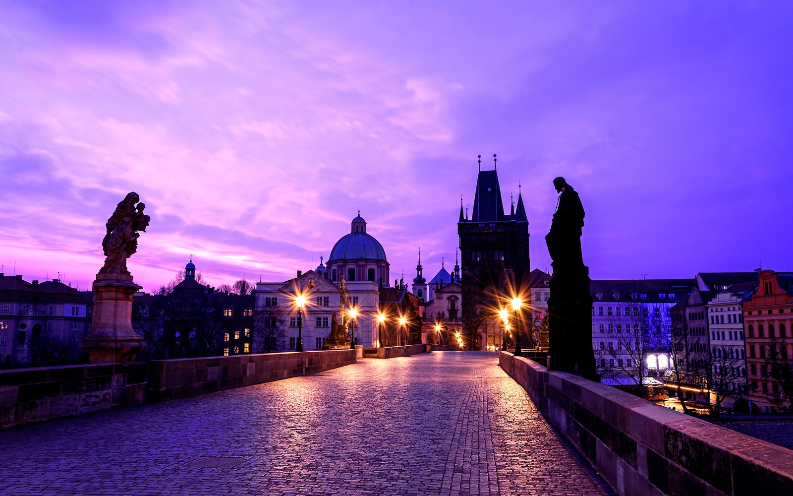 Céu roxo acima de uma ponte com estátuas e edifícios ao fundo (ponte carlos, charles bridge, castelo de praga, marco, noite)