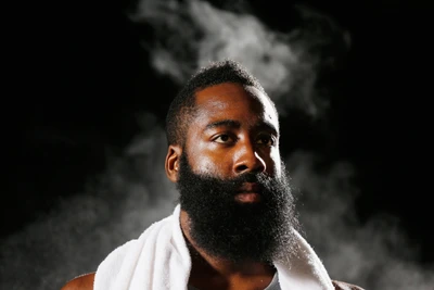 James Harden mit einem auffälligen Bart und konzentriertem Ausdruck, umgeben von einem nebligen Hintergrund.