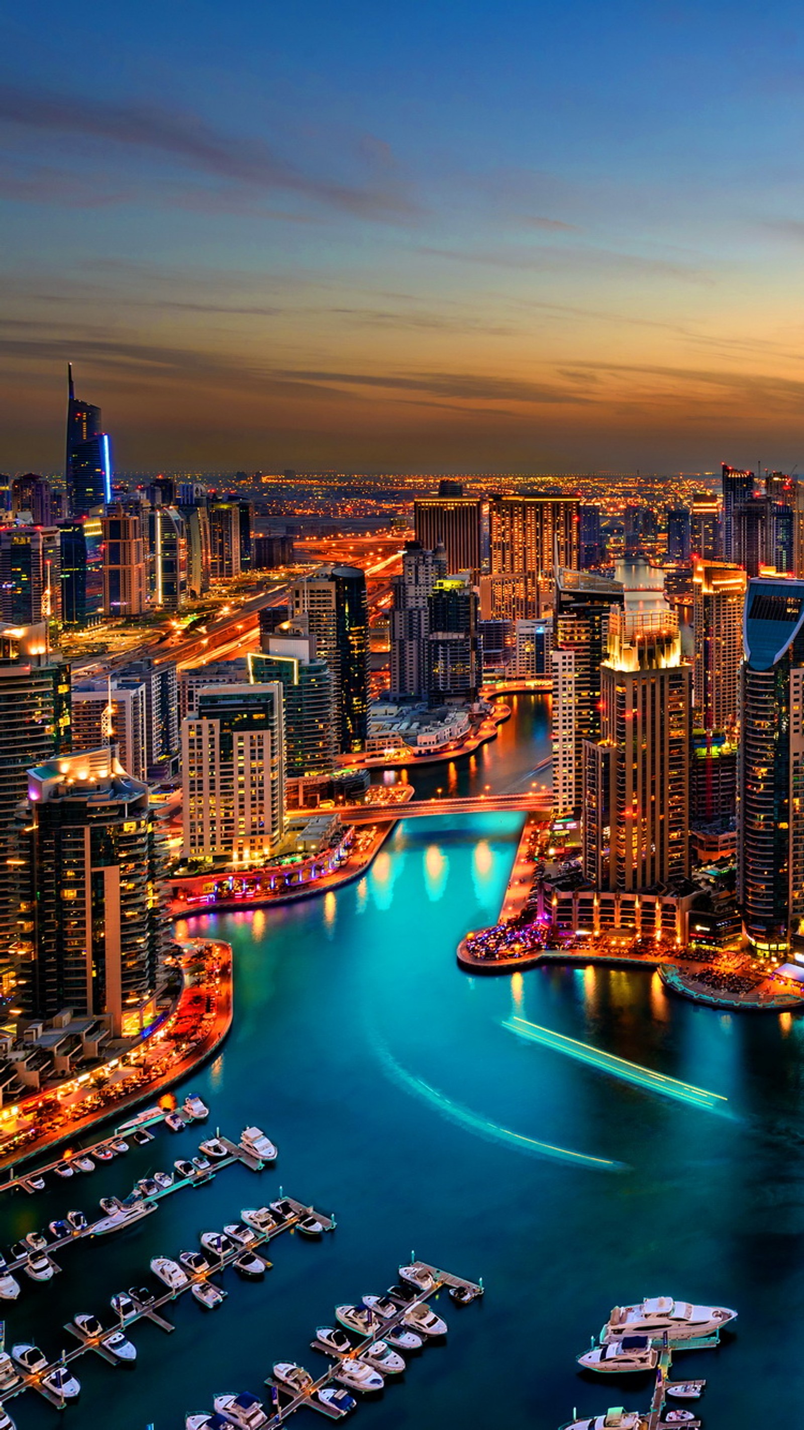 Vue d'une ville la nuit avec des bateaux sur l'eau (bateaux, dubaï, dubai, lumières, port)