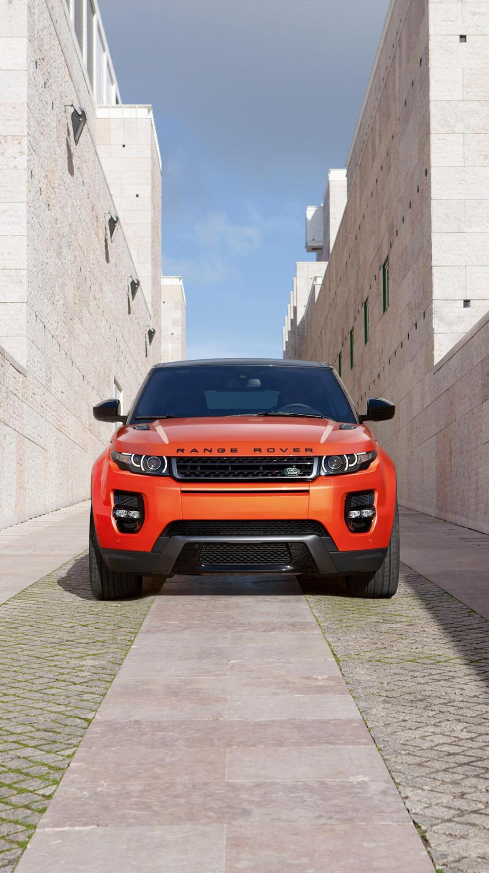 A close up of a red car parked on a brick road (car, pink, range rover)