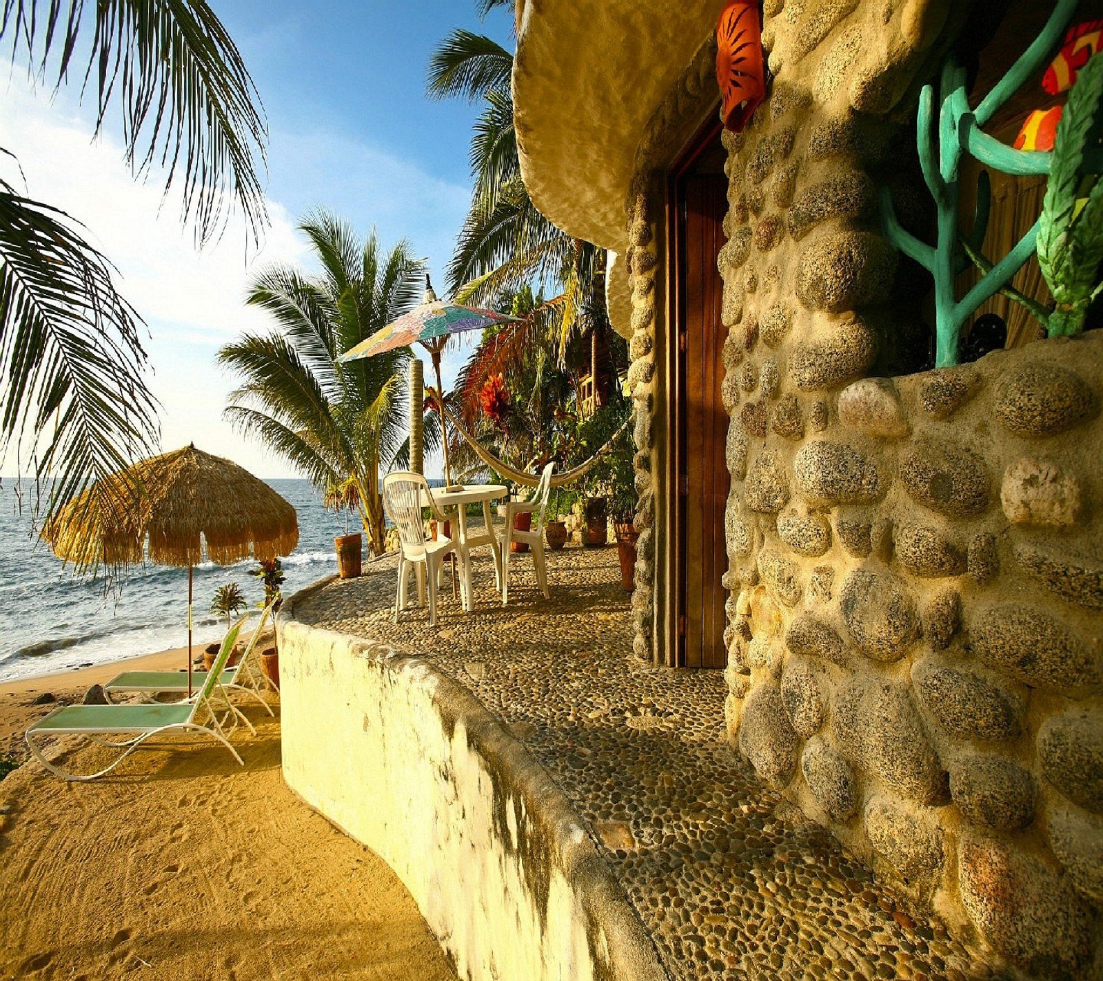 There is a stone wall with a beach umbrella and chairs (nature)