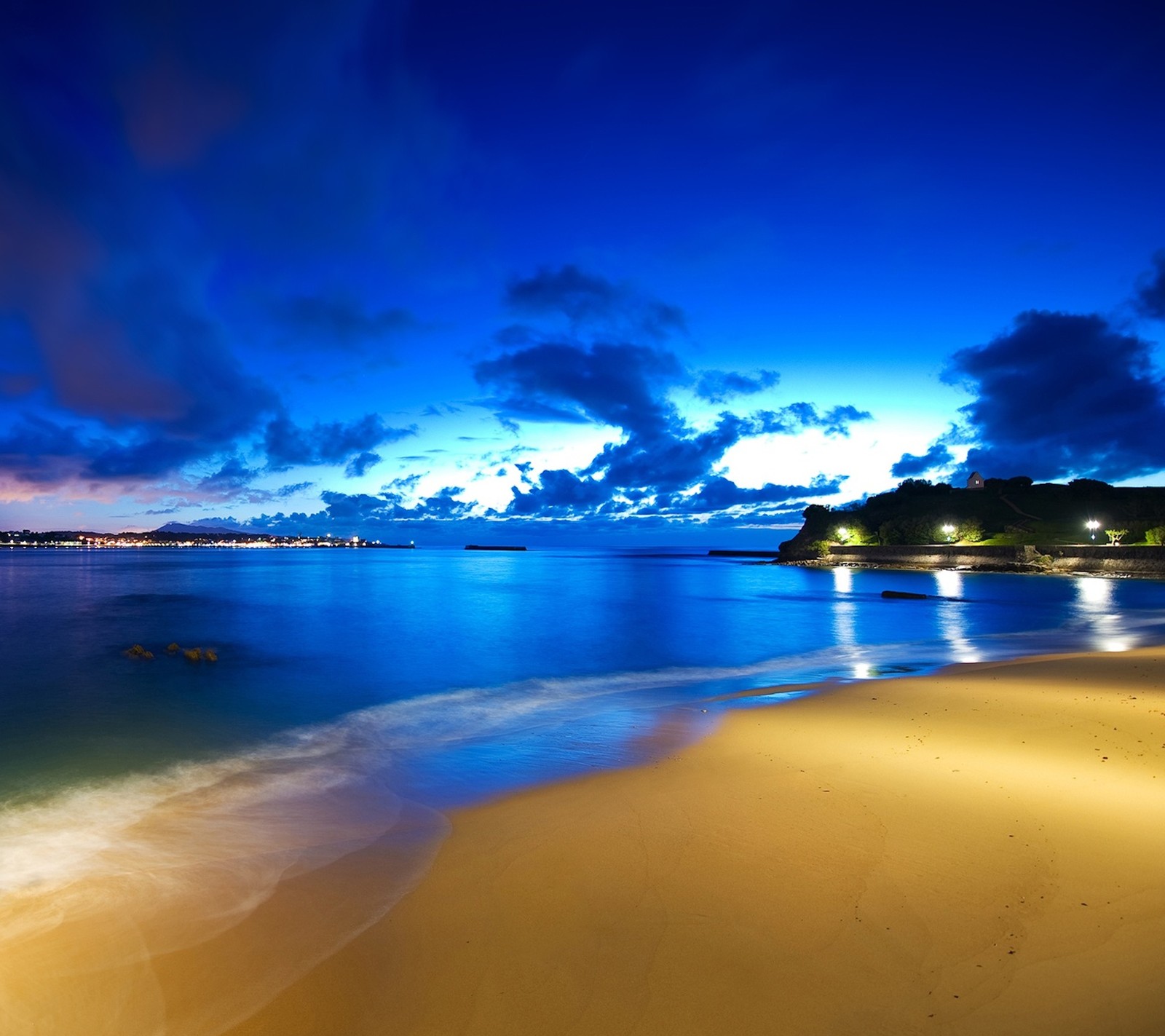 Imagen borrosa de una playa de noche con un bote en el agua (océano, vista)