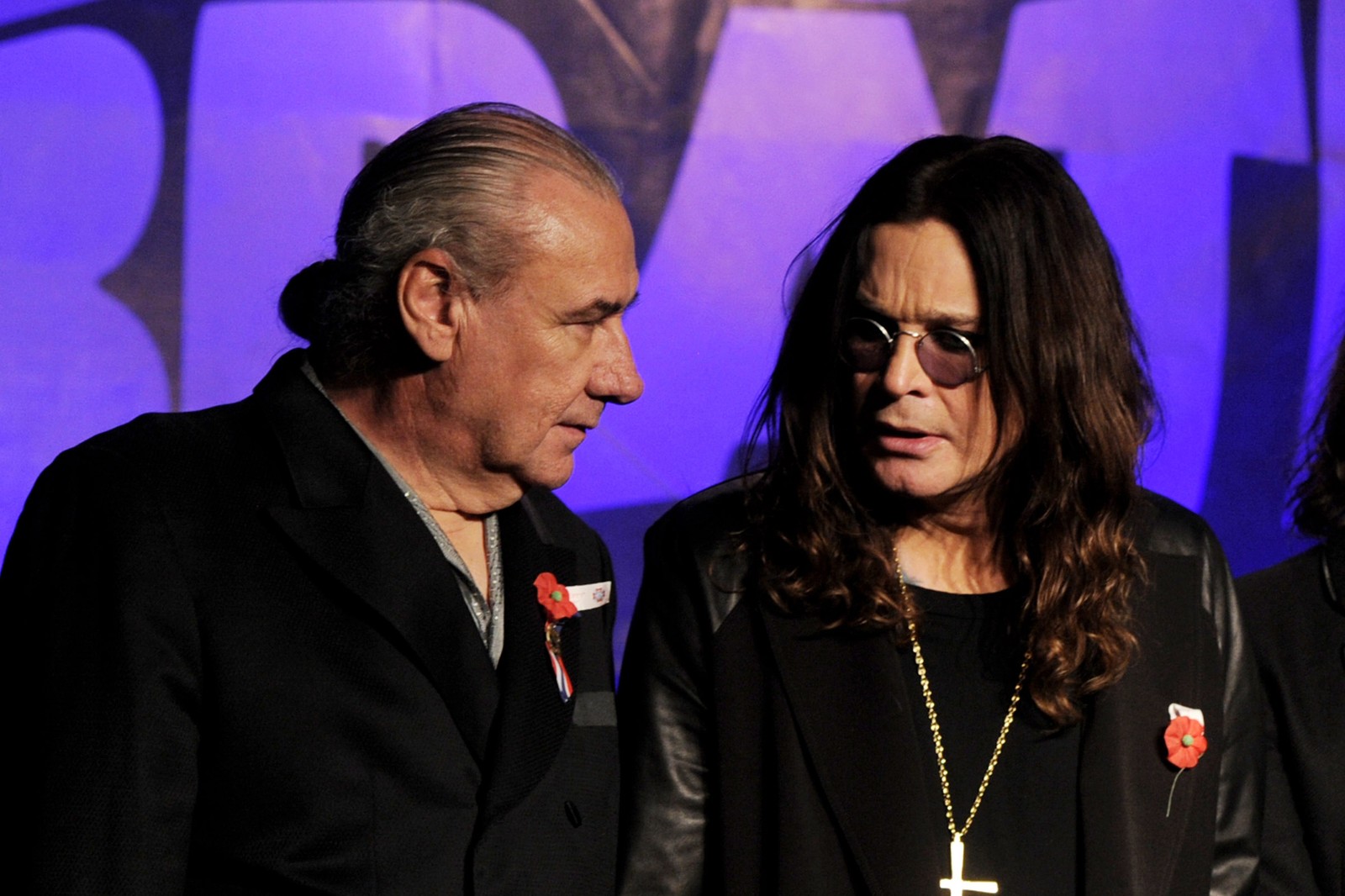 Una imagen de un hombre y una mujer de pie uno al lado del otro (bill ward, ozzy osbourne, black sabbath, heavy metal, baterista)