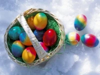 Colorful Easter eggs in a basket on snow.