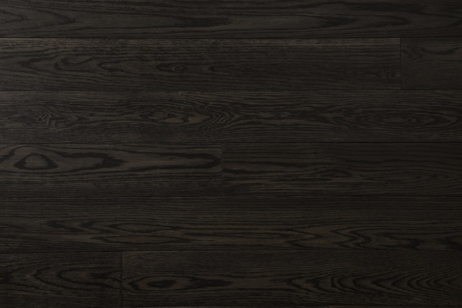 A close up of a black wood floor with a white wall (wood flooring, wood stain, laminate flooring, floor, hardwood)