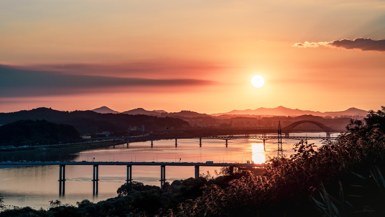 Une vue d'un pont sur une rivière avec un coucher de soleil en arrière-plan (coucher de soleil, crépuscule, eau, horizon, lever de soleil)