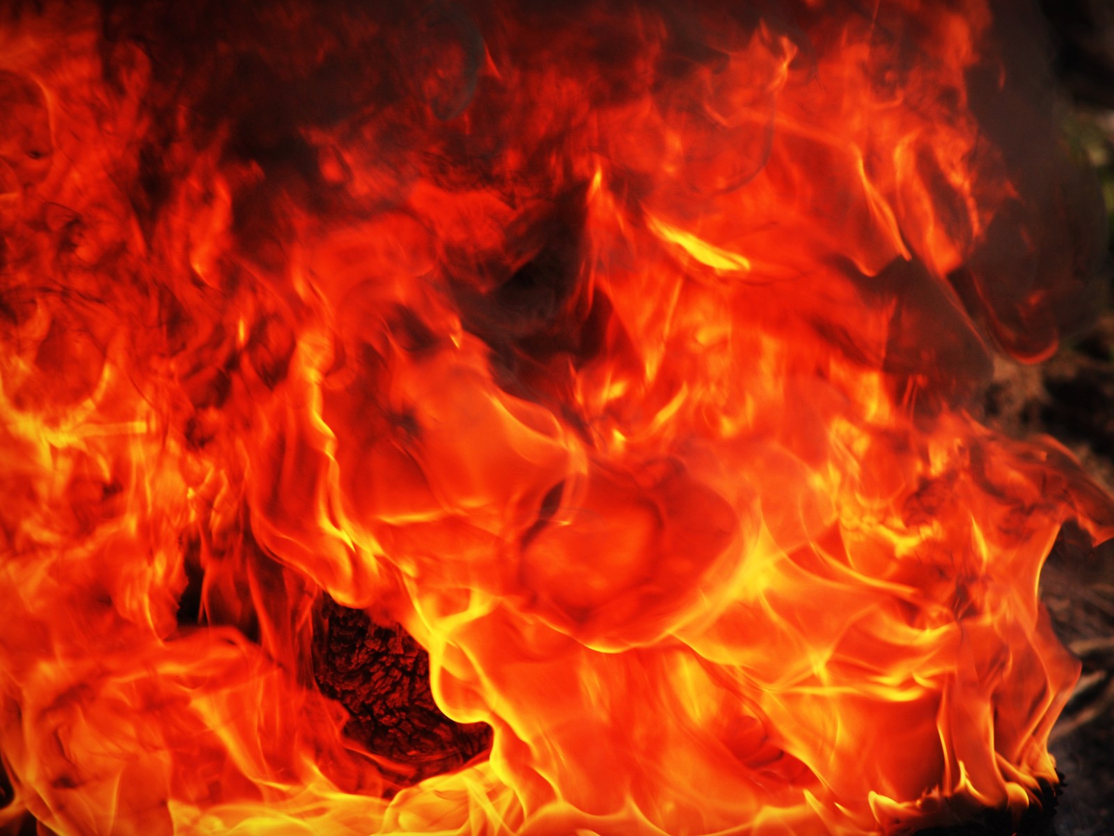 Des flammes brûlent dans une grande poêle en métal sur une cuisinière. (flamme, feu, chaleur, orange, enfer)