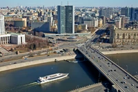 Un paysage urbain vibrant avec une métropole animée, des gratte-ciels, un cours d'eau sinueux et un pont fréquenté, mettant en valeur la vie urbaine dynamique le long de la rivière Moskva.