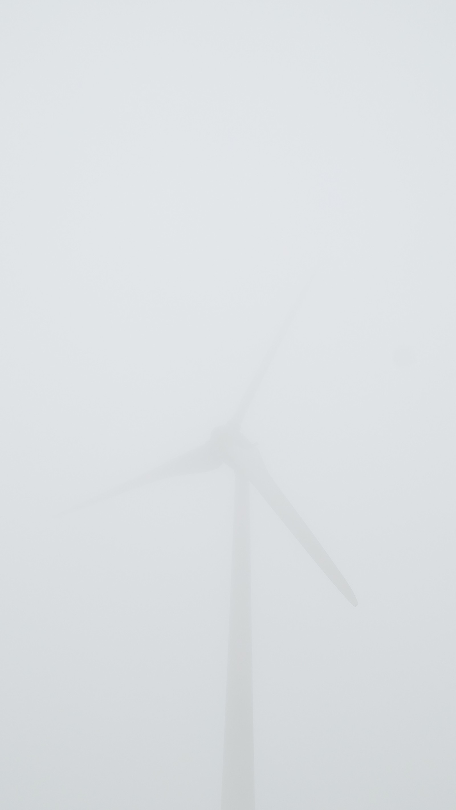 Vue aérienne de collines dans le brouillard par un jour brumeux avec une éolienne (brume, brumeux, gris, paysage, monochrome)