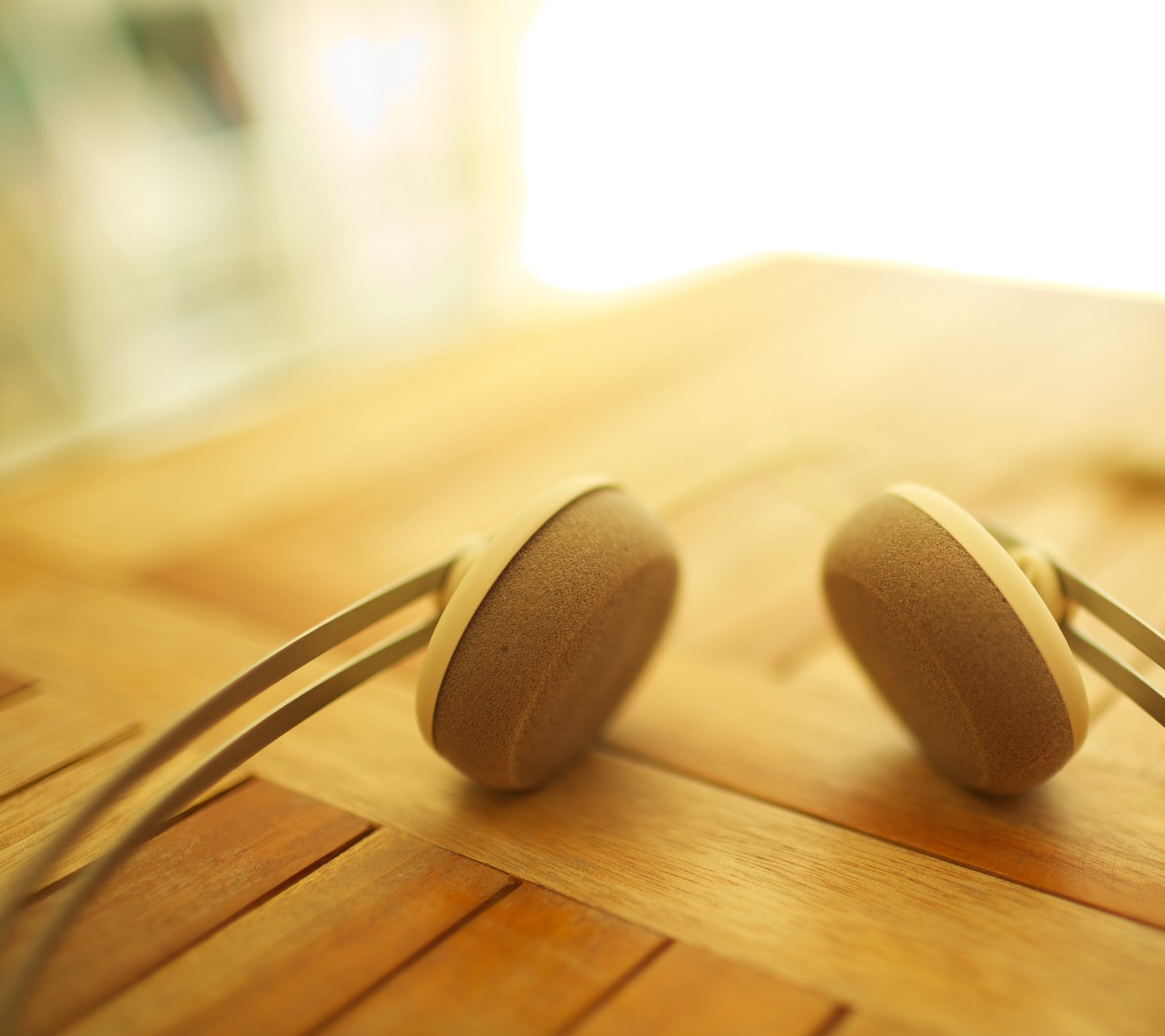 Hay dos auriculares sobre una mesa de madera con un fondo borroso (head set, música)