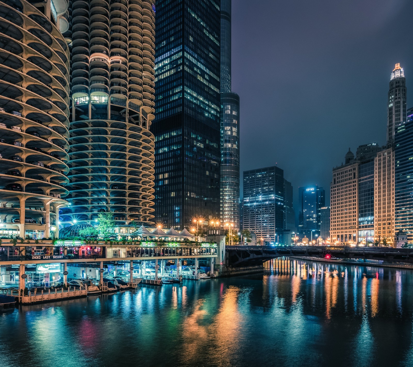 Una vista panorámica de una ciudad de noche con un río y un puente (chicago, ciudad, rio, urbano)