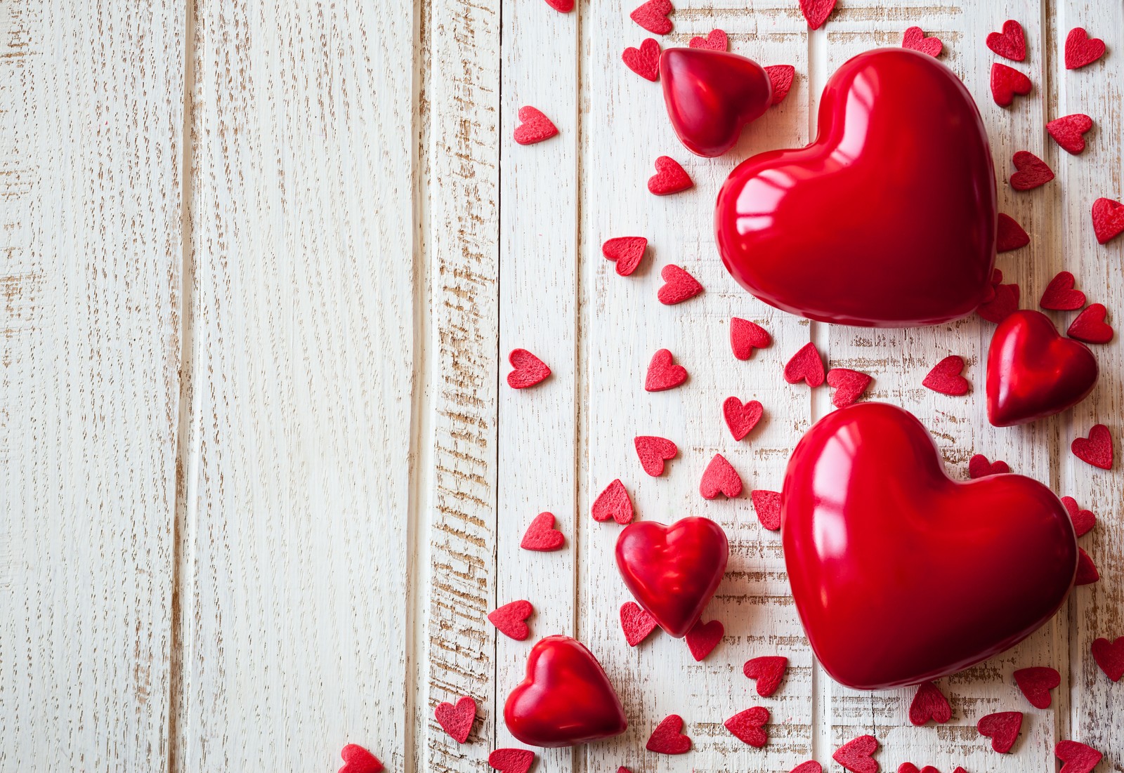 Deux cœurs rouges sont éparpillés sur une surface en bois blanc (cœur, saint valentin, amour, anniversaire, mariage)