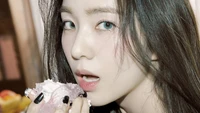 Irene de Red Velvet savourant un dessert coloré, mettant en valeur ses traits frappants et son regard captivant.