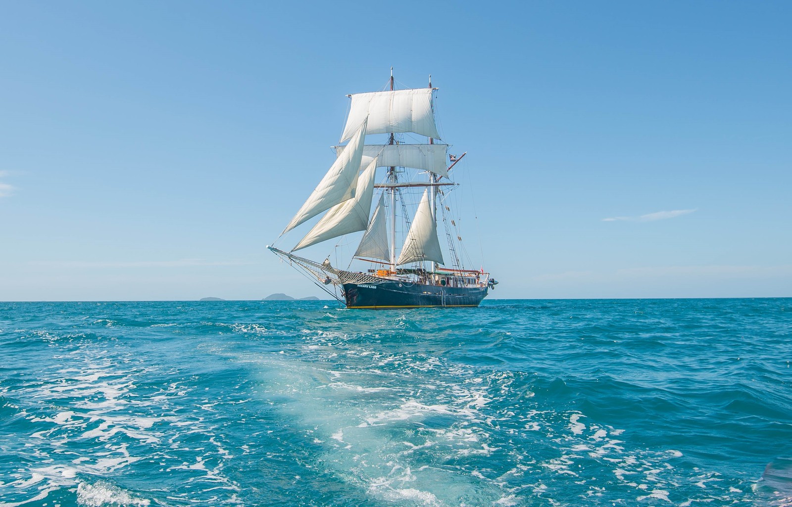 Un velero navegando en el océano aberto con cielo azul (barco, barco de vela, brigantina, yate, goleta)