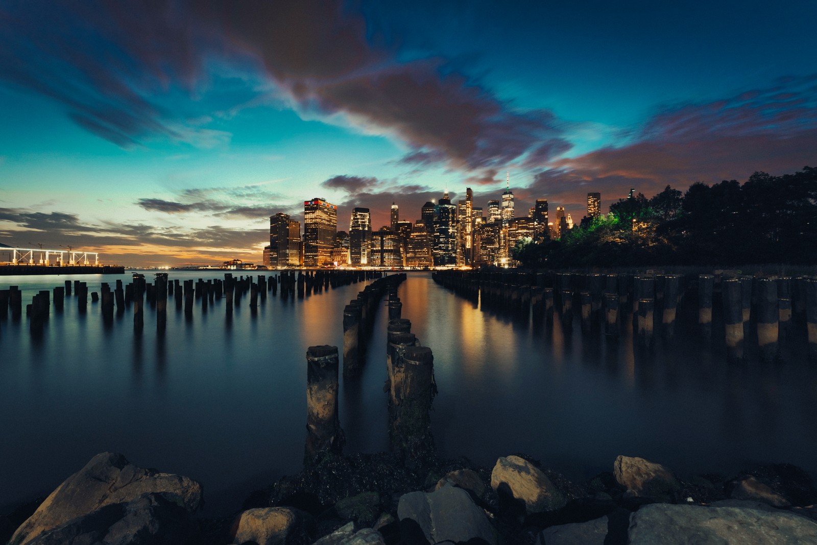 Blick auf die stadtsilhouette bei nacht vom wasser aus (new york city, abend, dämmerung, sonnenuntergang, stadtlichter)