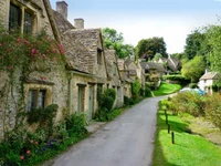 Charmantes cottages des Cotswolds dans le village de Bibury avec une verdure luxuriante et un chemin en pierre