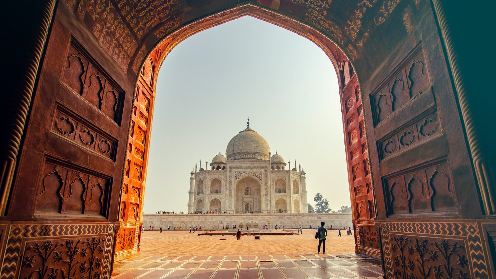 Arabischer blick auf ein gebäude durch einen türrahmen mit einer person, die in der ferne geht (taj mahal, agra fort, neue 7 weltwunder, denkmal, licht)