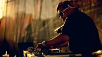 Mixage de DJ au coucher du soleil : Un disc-jockey en action avec des écouteurs et des lunettes