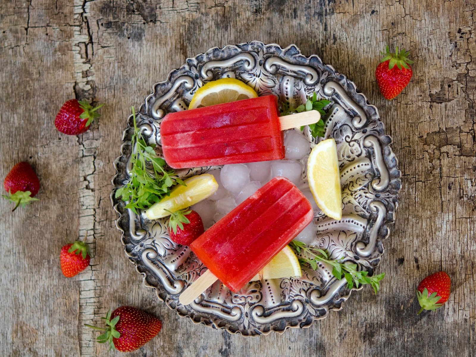 A close up of a plate of pops with lemon slices and strawberries (strawberry, fruit, food, juice, recipe)