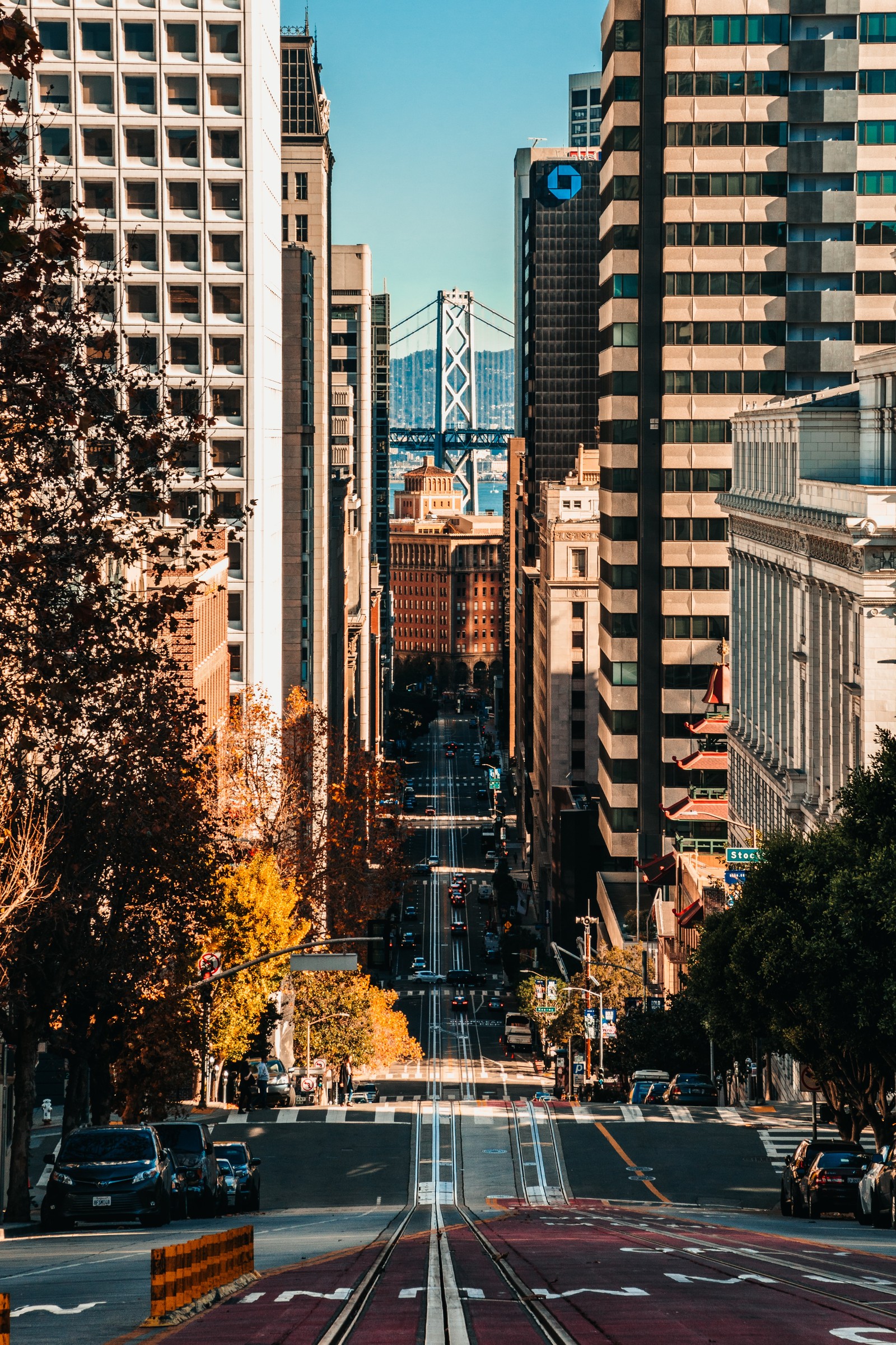 Hay una vista de una calle de la ciudad con un puente al fondo (edificio, rascacielos, día, ligero, árbol)