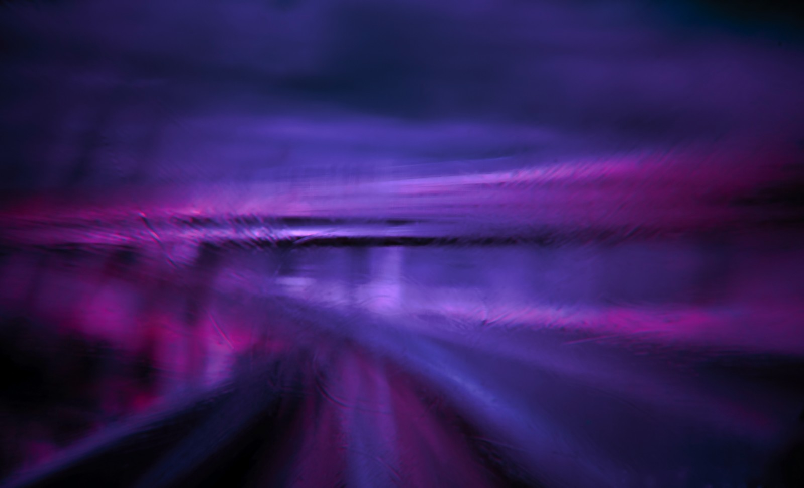 Purple and black photograph of a train traveling through a tunnel (blue, violet, purple, light, red)