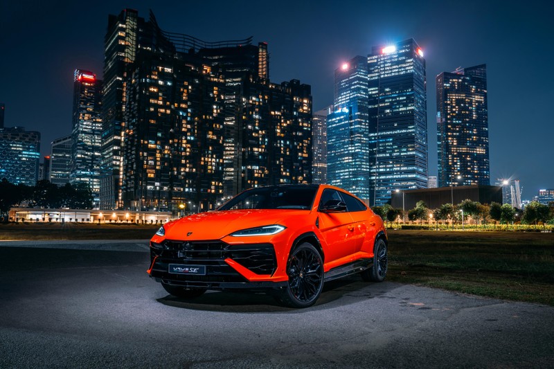 Ламб suv припаркован перед городским горизонтом ночью (lamborghini urus se, сингапур, 2024, гибридный внедорожник, 5k)