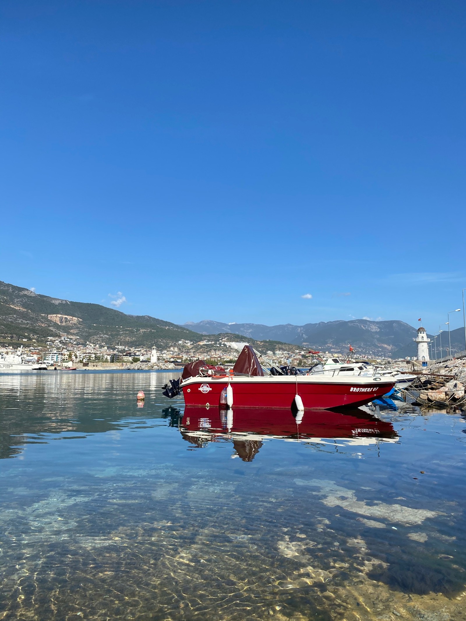 Há um barco vermelho que está na água (reflexo, água, embarcação, barco, montanha)