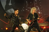 Dynamische Darbietung von Adam Lambert und Brian May, die elektrisierende Musik und Kunst bei einem Rockkonzert zeigt.