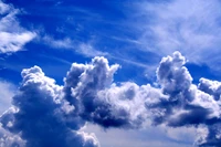 Des nuages cumulus majestueux sous un ciel bleu serein, illuminés par une douce lumière du soleil.