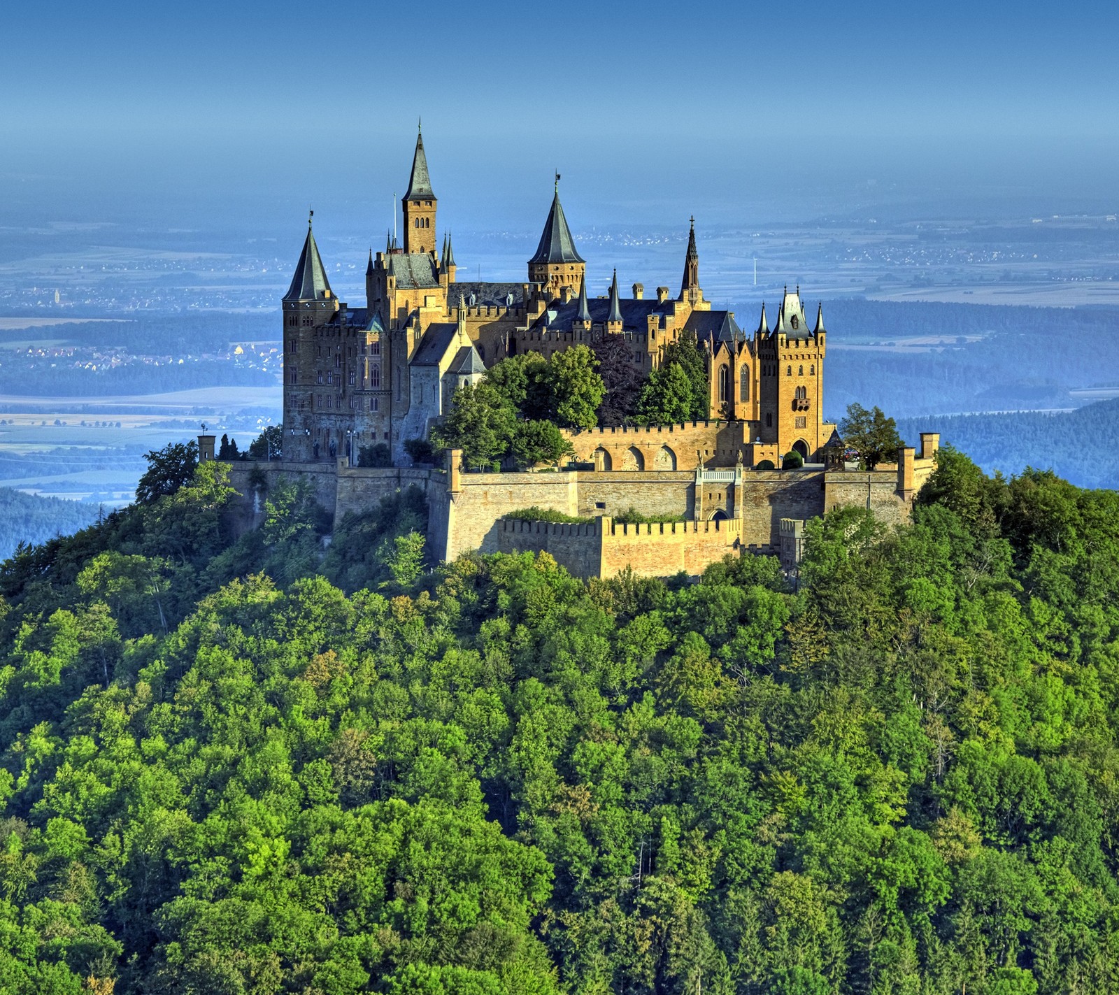 Un castillo en una colina con árboles y un cielo azul (castillo, hohenzoller)